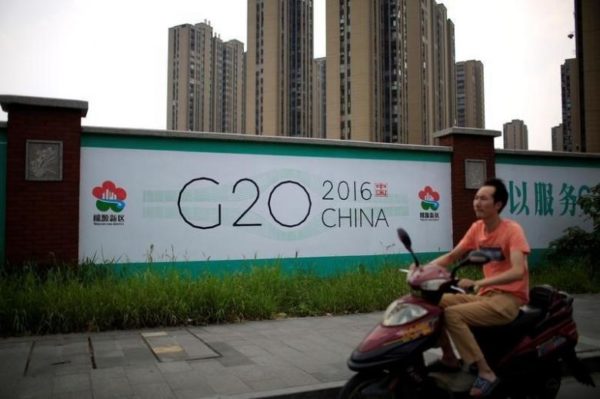 A man rides an electronic bike past a billboard for the upcoming G20 summit in Hangzhou, Zhejiang province, China, July 29, 2016. Picture taken July 29, 2016. REUTERS/Aly Song
