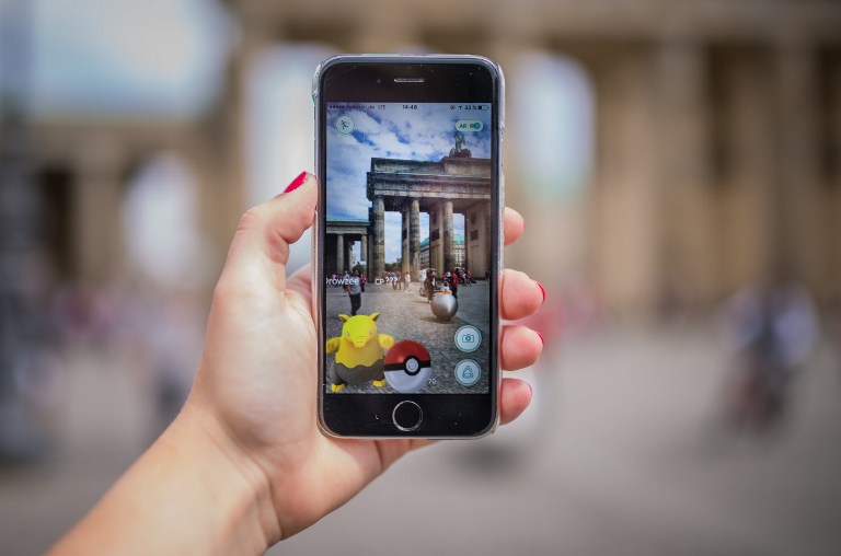 Eine Frau, die am Brandenburger Tor in Berlin Pokémon Go spielt.